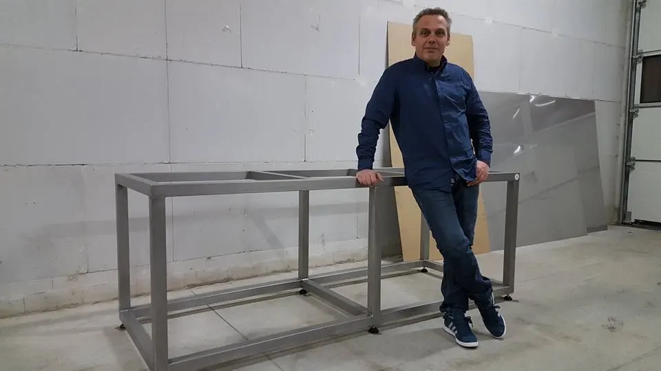 Medewerker van Coraltech leunt tegen een RVS-frame in de werkplaats