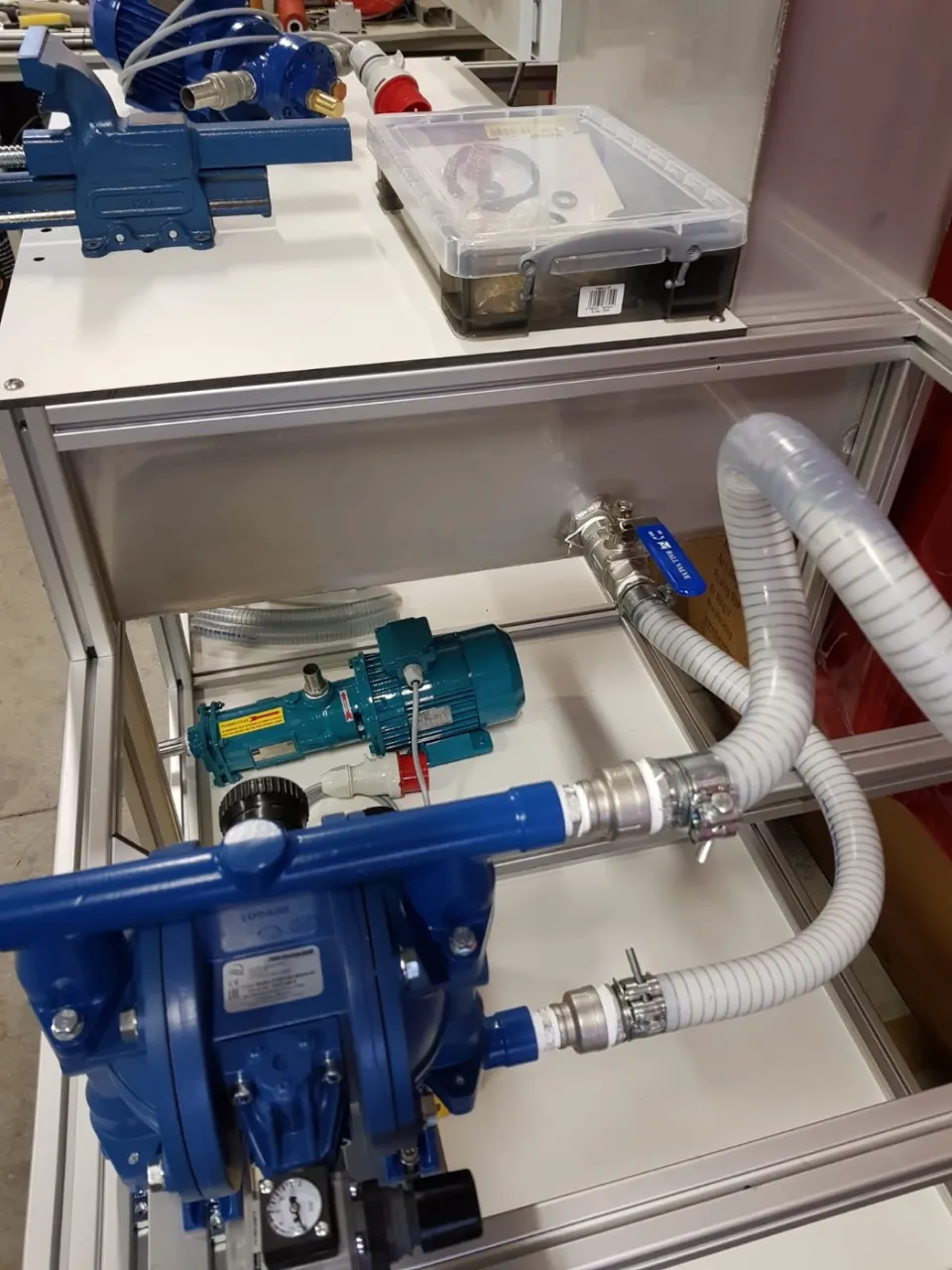 Pompopstelling met blauwe membraanpomp en slangen in een RVS-bak